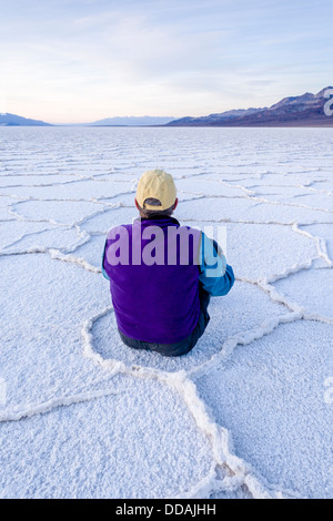 Ein Mann sitzt in geometrischen Mustern Salzpfanne in der Nähe von Badwater im Death Valley Nationalpark, Kalifornien. Stockfoto