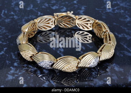 Gold-Armband mit Diamant-Chips vor einem dunklen Hintergrund. Stockfoto