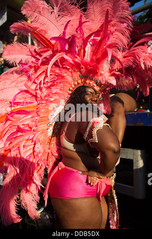 Eine große schwarze Frauen in gekleidet in rosa und riesigen roten Federn-Show von ihr Outfit mit Haltung auf dem Notting Hill Carnival. Stockfoto