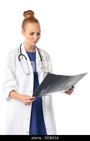 Hübsche junge Frau Doktor stehen ein Röntgenbild mit einem ernsten Ausdruck zu studieren, da sie die Prognose oder die Diagnose eines Patienten isoliert auf weiss geprüft Stockfoto
