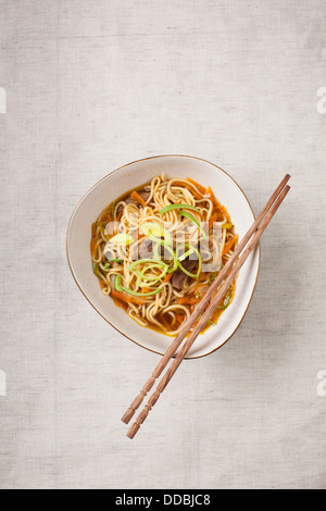 Asiatische Nudeln mit Schweinefleisch und Gemüse auf Textil-Hintergrund Stockfoto
