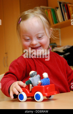 Dresden, Deutschland, ein Mädchen mit Down-Syndrom mit einem roten Auto spielen Stockfoto