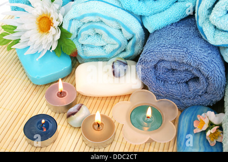 Stapel Handtücher, Seifen, Kerzen, Steinen, Blumen auf Matten Hintergrund. Stockfoto