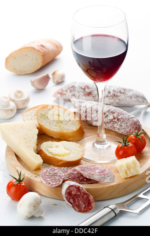 Weinglas mit Rotwein und Auswahl an Käse und Früchte auf weißem Hintergrund Stockfoto