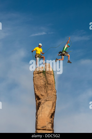 Team von männlichen Bergsteigern erobern die Gipfel von einem anspruchsvollen Rock-Turm. Stockfoto