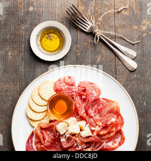 Platte mit verschiedene Snack Schinken, Salami, Käse und Honig Stockfoto