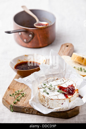 Gebackener Camembert Käse mit Thymian und geröstetem Brot auf Holzbrett Stockfoto