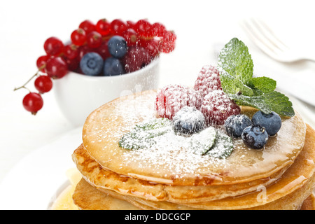 Haufen von leckere handgemachte Pfannkuchen mit Honig, Himbeeren und Heidelbeeren garniert Stockfoto