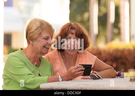 Senioren Freunde betrachten ein smart Phone und lächelnd Stockfoto