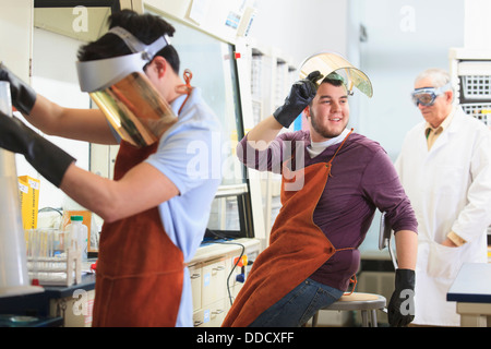 -Studenten und Professor tragen einer Schutzausrüstung bei der Arbeit im Chemielabor Stockfoto