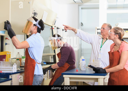 -Studenten und Professor tragen einer Schutzausrüstung bei der Arbeit im Chemielabor Stockfoto