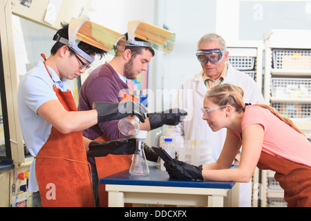 -Studenten und Professor tragen einer Schutzausrüstung bei der Arbeit im Chemielabor Stockfoto