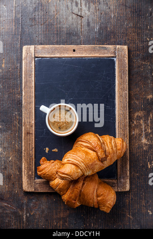 Tasse Kaffee und Croissants an Vintage Schiefer Tafel Stockfoto