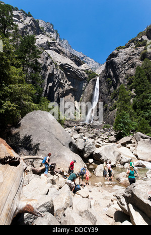 Touristen im Wasser Abkühlung an einem heißen Sommertag, unteren Yosemite Fall im Hintergrund. Yosemite Nationalpark, Kalifornien, USA. Stockfoto