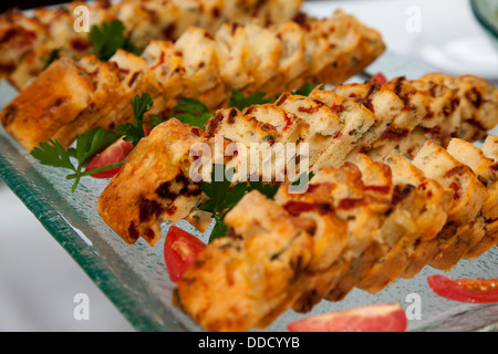 Getoastete Scheibe Brot mit Käse Tomaten Petersilie serviert auf rechteckige Glas Fach auf Tisch Stockfoto