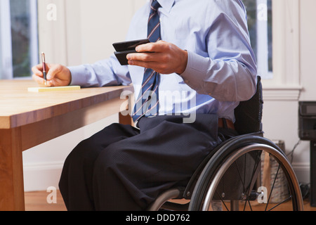 Geschäftsmann mit Querschnittslähmung im Rollstuhl mit einem smartphone Stockfoto