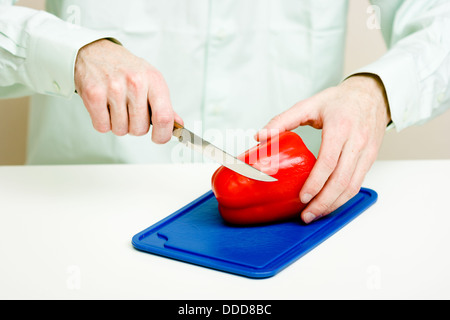 Man schneidet Pfeffer. Hände mit Messer hautnah Stockfoto