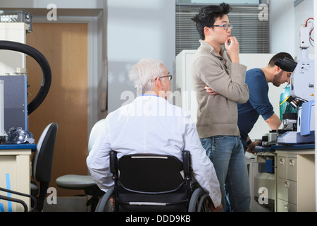 Professor mit Muskeldystrophie mit Ingenieurstudent Blick auf Röntgen-Fluoreszenz-Analyzer in einem Labor arbeiten Stockfoto