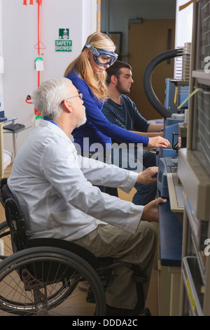 Professor mit Muskeldystrophie, Beratung, engineering-Studenten im Chemielabor an thermogravimetrische Analysatoren arbeiten Stockfoto