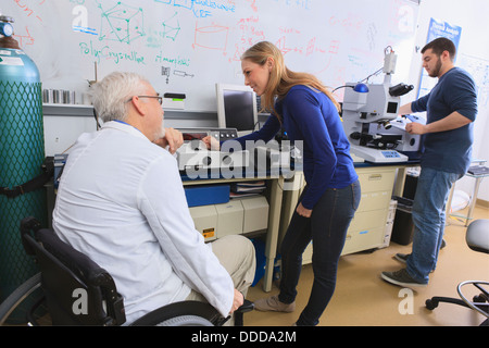 Professor mit Muskeldystrophie, Beratung, engineering-Studenten in Chemielabor auf Röntgen-Fluoreszenz-Analysatoren Stockfoto