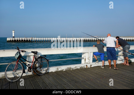 Sohn, Vater und Großvater Angeln mit Angelrute vom Pier entlang der Nordsee Küste in Nieuwpoort / Nieuport, Belgien Stockfoto