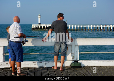 Sohn, Vater und Großvater Angeln mit Angelrute vom Pier entlang der Nordsee Küste in Nieuwpoort / Nieuport, Belgien Stockfoto