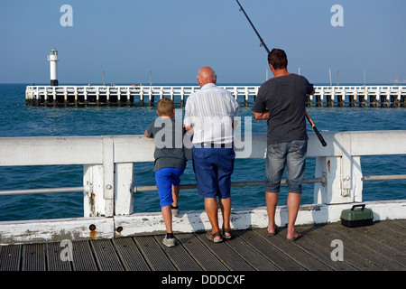 Sohn, Vater und Großvater Angeln mit Angelrute vom Pier entlang der Nordsee Küste in Nieuwpoort / Nieuport, Belgien Stockfoto