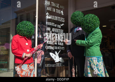 Runde, runde, grüne Kopfbedeckung, baumbestandene künstliche Perücken, Kopfanlage, getragen von Straßenkünstlern in Kendal, Cumbria, Großbritannien. August 2013. Mintfest, Kendal's International Festival of Street Arts, The Potheads by Let's Circus, Fat Face Shop, ein Lakes Alive Weekend Event im Lake District, bei dem einige der besten aus der ganzen Welt auftraten, zeitgenössischer Tanz, Zirkus, Comedy, Musik, Eigenartige Gruppe draußen auf den Straßen. Stockfoto