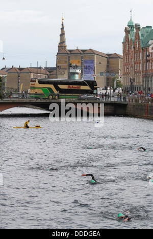 Kopenhagen, Dänemark. August 2013. 2.400 Schwimmen rund um das Parlamentsgebäude, das Schloss oder den Palast Christiansborg im Zentrum Kopenhagens im 2.000 m größten jährlichen Open-Water-Wettbewerb, in Dänemark, das Kopenhagener Schwimmen, organisiert vom dänischen Schwimmverband und der Zeitung Politiken. Schwimmer sind gerade an Børsbroen vorbeigegangen, dem goldenen Korckenzieherturm der Erlöserkirche im Hintergrund und der alten Börse rechts. Kredit: Niels Quist/Alamy Live News Stockfoto