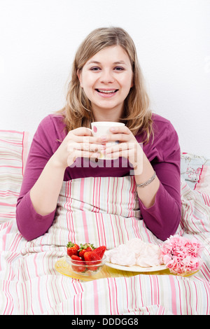 Glücklich schöne lächelnde junge Frau mit Kaffee und romantisches Frühstück im Bett. Stockfoto