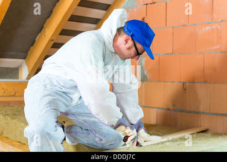 Arbeitnehmer insgesamt ist isolierendes Material mit Handschuhen und Messer schneiden. Stockfoto