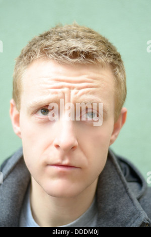 Junge blonde Mann trägt einen grauen grauen Mantel nachschlagen Stockfoto