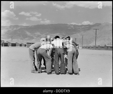 Im Manzanar Relocation Center in Kalifornien drängen sich Baseballspieler während eines Spiels. Dieses Foto zeigt einen Moment in einem der Internierungslager, in dem japanische Amerikaner während ihrer Inhaftierung Sport und Erholung pflegten. Stockfoto