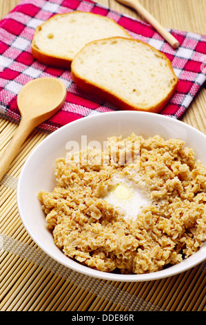 Brei in Schüssel mit Butter auf einem Holztisch Stockfoto