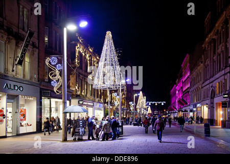 Winterabend, Buchanan Street Glasgow. Shopper & Pendler passieren die Geschäfte und eine Gruppe von Menschen beobachten einen Ballon-Bildhauer Stockfoto