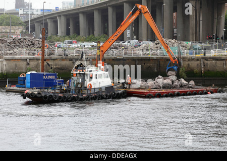 Arbeiten zur Reparatur des eingestürzten Gehwegs am Anderston Quay am Fluss Clyde mit einem Bagger, der von einem Lastkahn in Glasgow, Schottland, Großbritannien, arbeitet Stockfoto