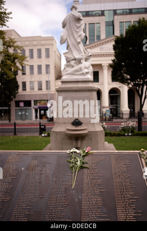 Ansicht von hinten das Titanic Memorial in Belfast Stadtzentrum entfernt. im Vordergrund liegt einige Blumen auf einem Bronze Sockel. Stockfoto