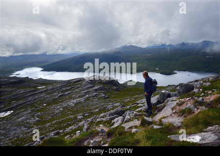 Ein Hügel Walker mit Blick auf Loch Assynt am östlichen Kamm des Spidean Coinich (ein Corbett) auf dem schottischen Berg Quinag. Stockfoto