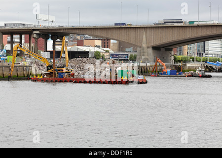 Arbeiten zur Reparatur des eingestürzten Gehwegs am Anderston Quay am Fluss Clyde mit einem Bagger, der von einem Lastkahn in Glasgow, Schottland, Großbritannien, arbeitet Stockfoto