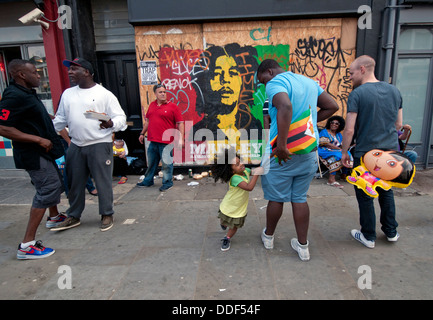 Gruppe von Freunden mit Kindern vor vernagelt Ladenfront im Westen Londons. Stockfoto
