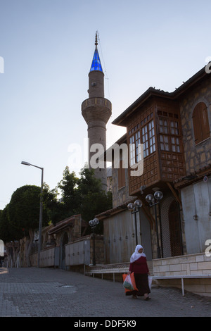 Eine ältere türkische Frau in traditioneller Kleidung geht mit ihr Einkaufen vorbei an der Moschee in Side, Türkei Stockfoto