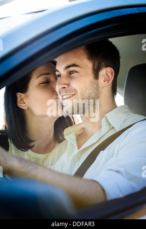 Paar im Auto - junge Frau küssen Mann im Auto während der Fahrt Stockfoto