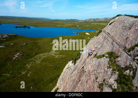 Kletterer auf sandsteinplatte mit blauem Himmel und See, in der Nähe von Gairloch, Nordwesten Schottland, Stockfoto