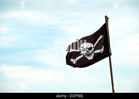 Zerfetzte Piratenflagge mit Totenkopf von Fahnenmast geflogen Stockfoto