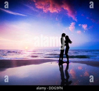 Romantisches Paar küssen am Strand bei Sonnenuntergang Stockfoto