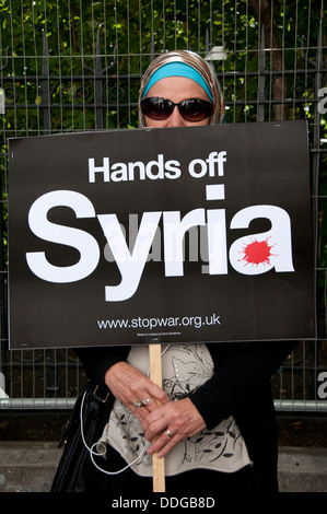 Demonstration gegen jede Intervention in Syrien.  Eine muslimische Frau trägt ein Kopftuch und Sonnenbrille hält ein Plakat. Stockfoto