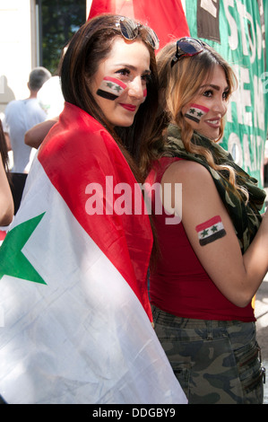 Demo gegen die Intervention in Syrien. Junge syrische Frauen mit Fahnen gemalt auf ihren Wangen und einer eingewickelt in eine Fahne. Stockfoto