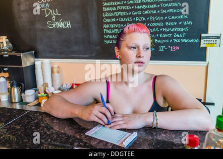 Hipster Mädchen in ihren Zwanzigern, arbeitet an Eisdiele und Piercings und bunten Haaren. Stockfoto