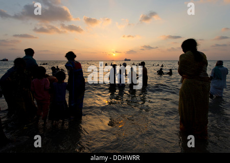 Hindu-Pilger nehmen ein heiliges Bad im Meer bei Sonnenaufgang am Ghat Agni Theertham Stockfoto
