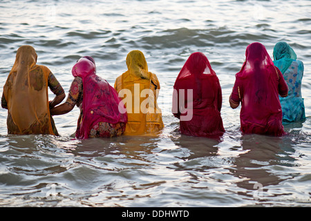 Hindu-Pilger Baden Frauen in bunten Saris, die unter einem Heiligen Om Meer vor Sonnenaufgang am Ghat Agni Theertham Stockfoto